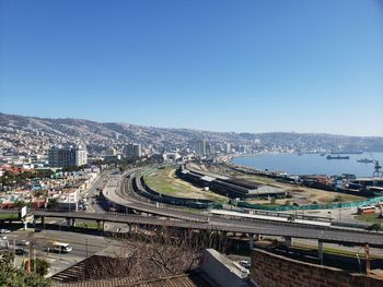 High angle view of road by buildings against clear blue sky