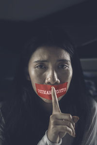 Close-up portrait of crying young woman with covered mouth with tape