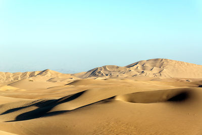 Scenic view of desert landscape against clear sky at huacachina