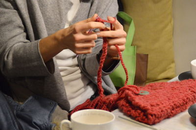 Midsection of woman knitting purse while sitting at home