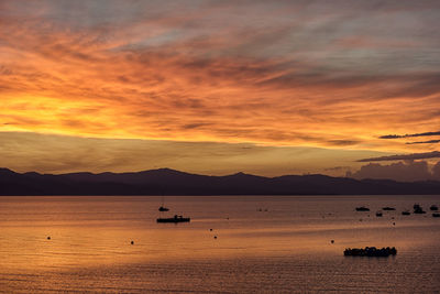 Boats sailing in sea against sky during sunset