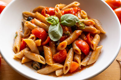 Italian pasta with tomato and olives. high angle view of fruits in container on table