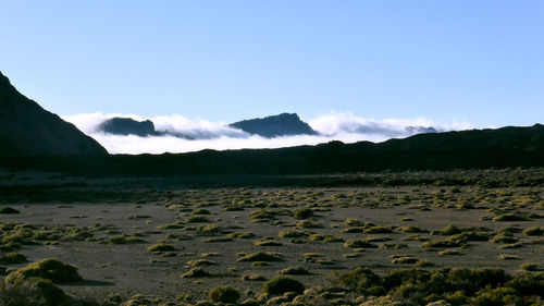 Scenic view of land and mountains against blue sky