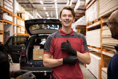 Smiling salesman looking away while talking to customer at hardware store
