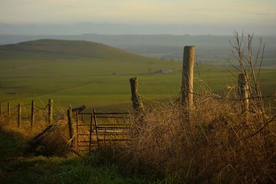 Wooden fence on field against sky