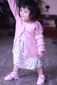 Full length of cute girl standing on pink indoors
