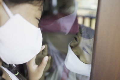 Close-up of girl and boy at window