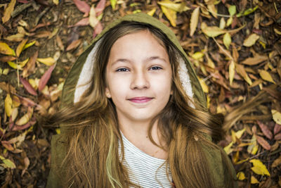 Portrait of smiling girl lying on autumn leaves