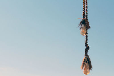 Low angle view of rope tied on wood against sky