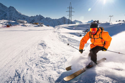 Freerider in a bright suit is skiing with big splashes of snow on a sunny day. young skier. big