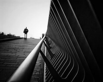Silhouette person walking on railing against sky