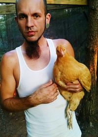 Portrait of man holding chicken