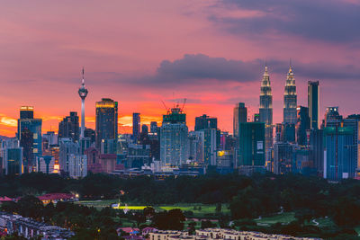 Buildings in city against cloudy sky during sunset