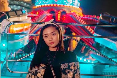 Portrait of young woman in amusement park ride at night