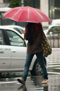 Midsection of woman with umbrella during rainy season