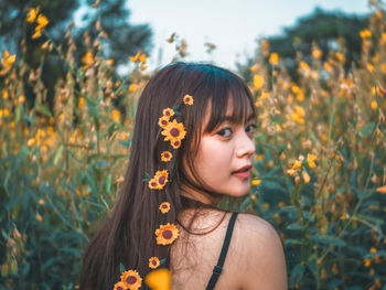 Portrait of woman wearing flowers amidst plants