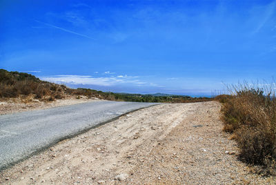Road amidst landscape against blue sky