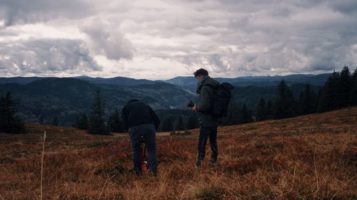 Rear view of man standing on mountain against sky