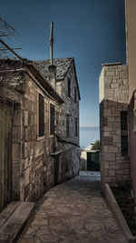 Footpath amidst old buildings against sky