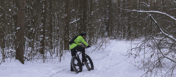 Rear view of man cycling on snow covered land