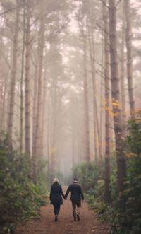 Rear view of people walking in forest