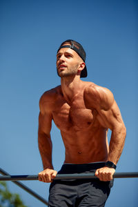 Low angle view of shirtless man standing against clear sky