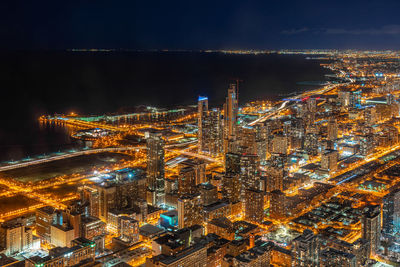 Illuminated cityscape by river at night