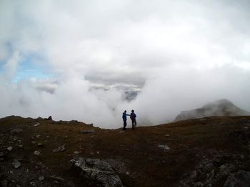 Rear view of people walking on mountain against sky