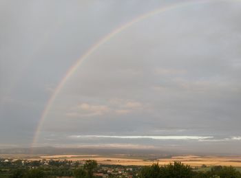 Rainbow over landscape against cloudy sky