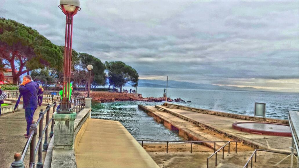 water, sky, cloud - sky, lifestyles, sea, leisure activity, railing, men, cloudy, pier, rear view, nautical vessel, person, full length, built structure, transportation, tree, weather