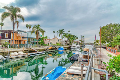 Boats moored in swimming pool by building against sky