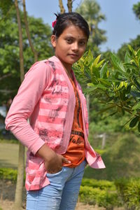 Portrait of young woman standing against plants