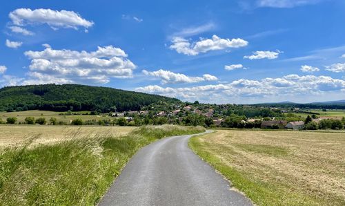 Road amidst field against sky