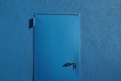 Close-up of closed door on blue wall