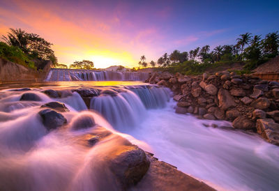Scenic view of waterfall against sky during sunset