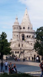 Tourists on top of historic building against sky