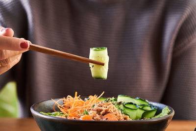 Midsection of person holding rice in bowl on table