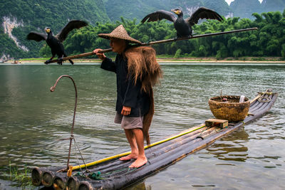 Man with birds on wooden rafts in lake