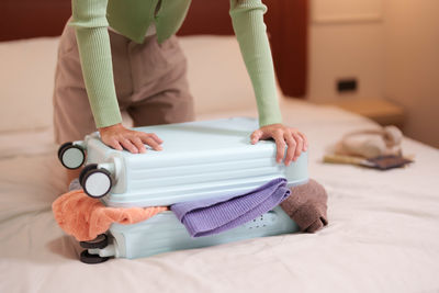 Low section of woman sitting on bed at home