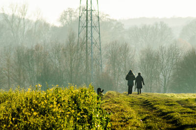 Rear view of people walking on field during winter