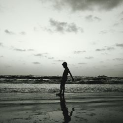 Silhouette man standing on beach against sky during sunset