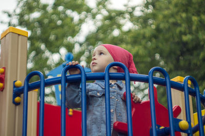 Low angle view of girl on jungle gym at park