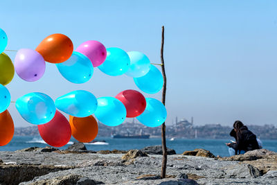 Multi colored balloons on rocks against blue sky