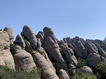 Low angle view of rocks against clear blue sky