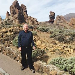 Happy mature man standing against rock formations