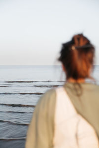 Side view of woman looking at sea against clear sky