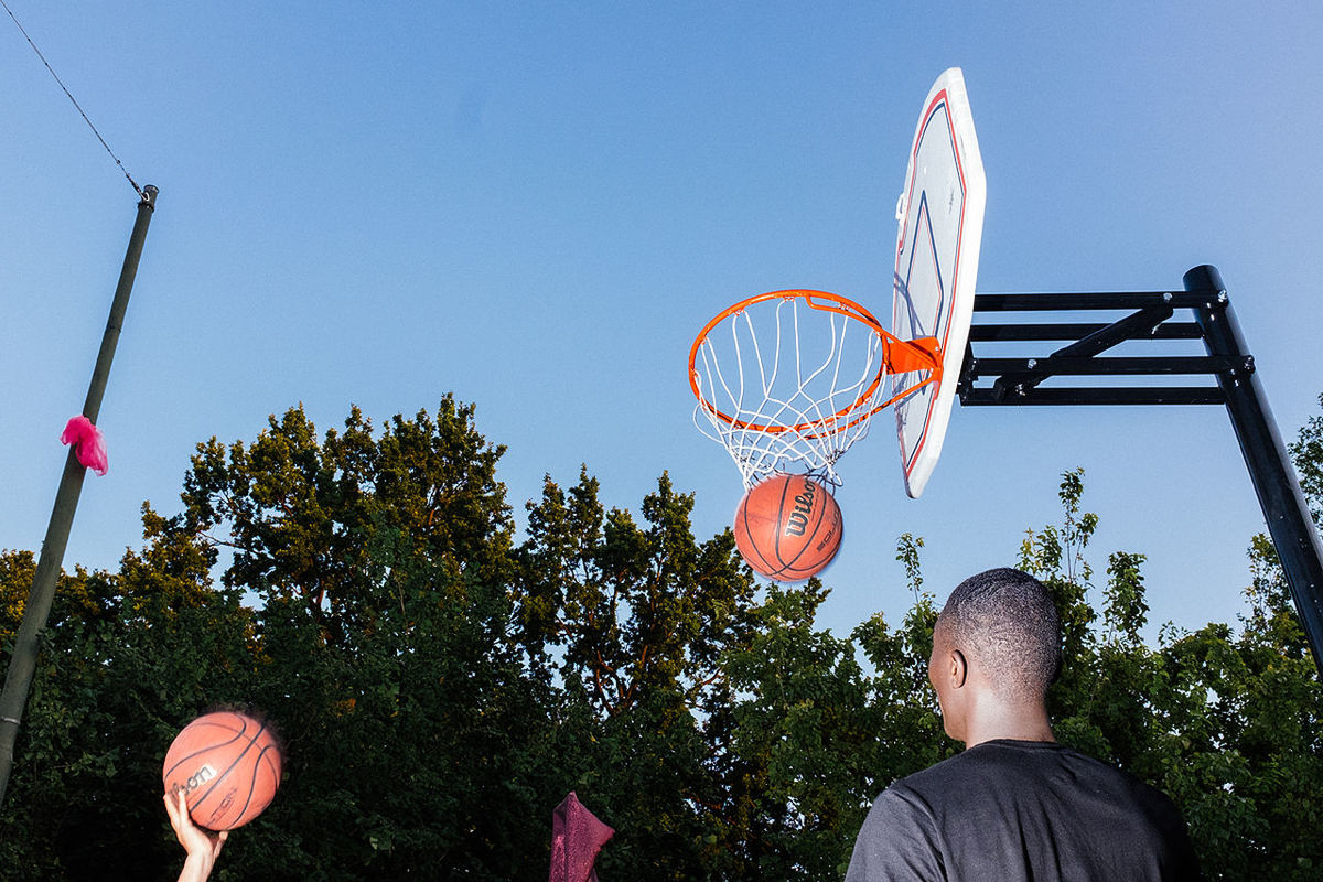 LOW ANGLE VIEW OF MAN PLAYING BASKETBALL HOOP AGAINST SKY