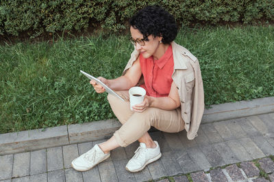 Young man using mobile phone while sitting on ground