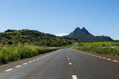 Road by mountains against clear sky