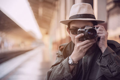 Portrait of man photographing with camera at railroad station platform